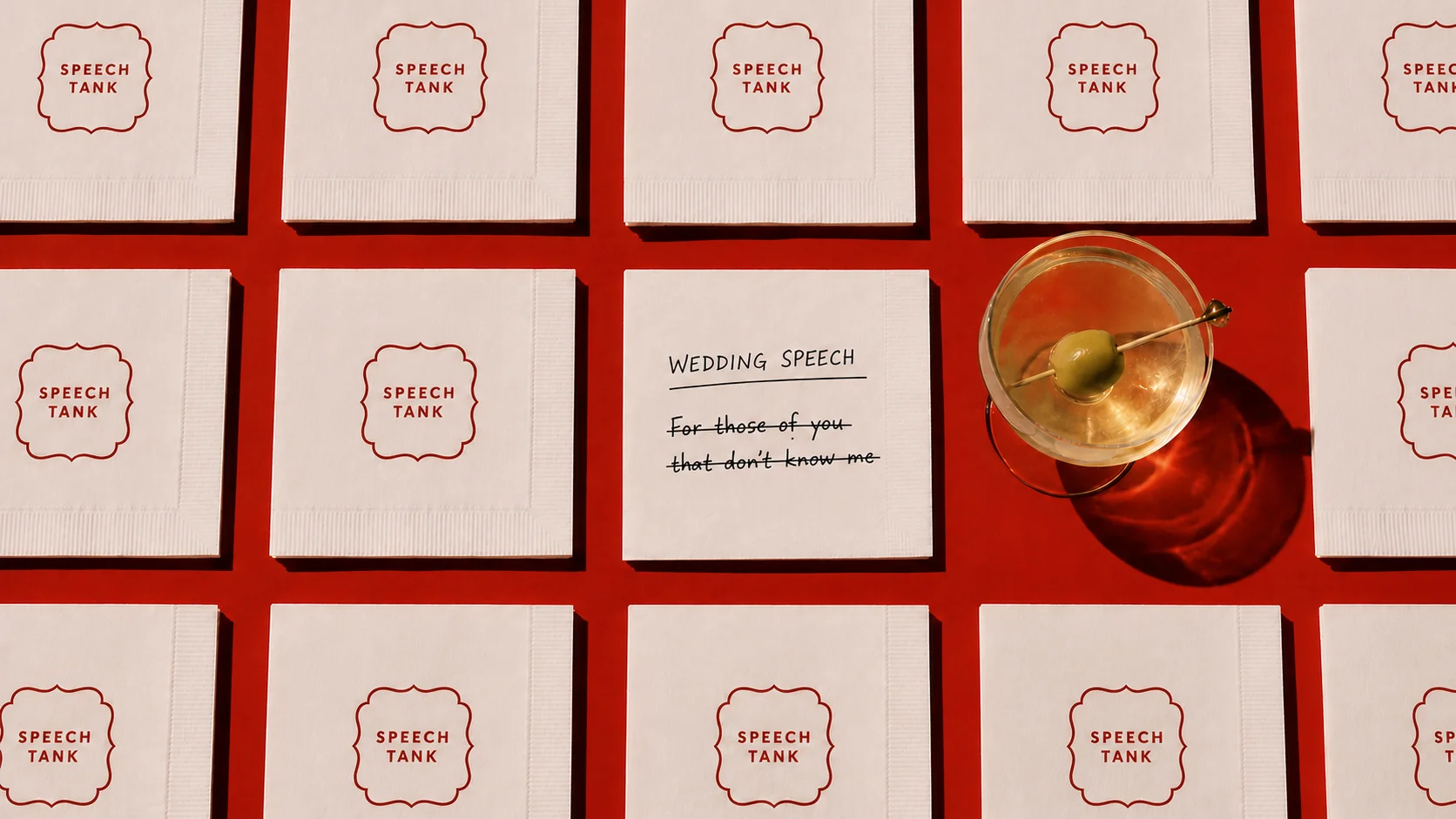 Speech Tank napkins arranged around a cocktail, with one napkin showing a crossed-out wedding speech opening